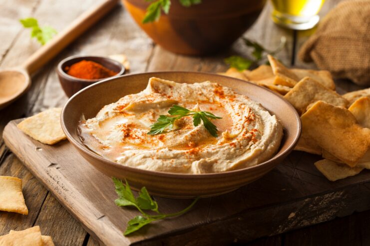 Classic Middle Eastern Hummus Presentation Classic hummus sprinkled with paprika and olive oil surrounded by fresh pita bread and herbs.