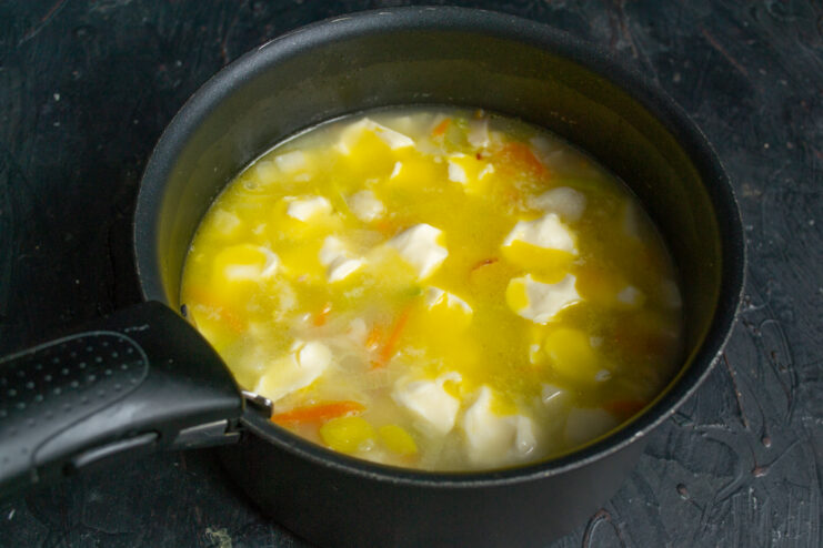 Shaping dumplings and adding them to the soup Dropping dumplings and processed cheese into a boiling soup pot
