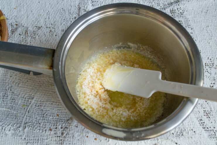 Melting butter and coconut Shredded coconut and butter melting in a heavy-bottomed saucepan
