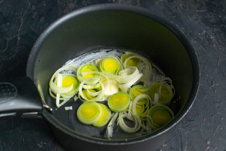 Sweating leeks over low heat to soften Sliced leek rings cooking in melted butter inside a pot