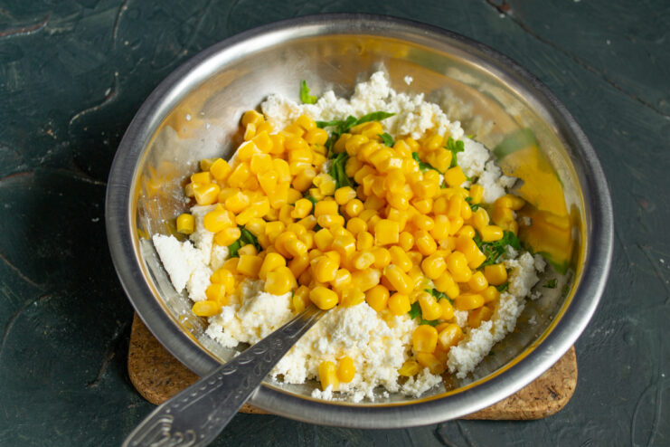 Folding canned corn into the pancake dough Sweet corn kernels added to the cheese and spinach mixture