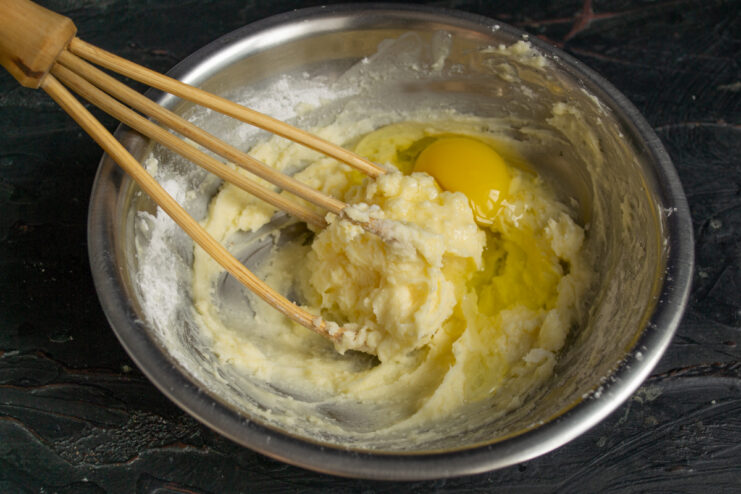 Adding the egg An egg added to the butter mixture in a metal bowl.