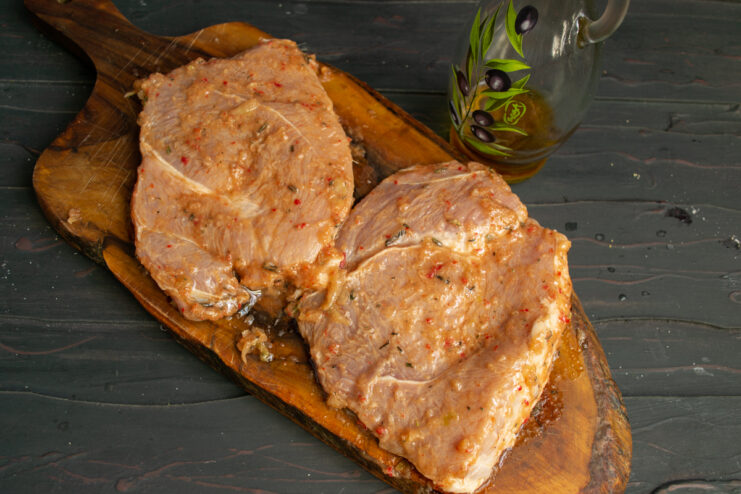 Preparing Meat for Searing Marinated pork pieces brushed with oil on a cutting board.