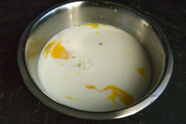 Pouring milk into the egg mixture in a bowl.