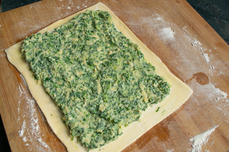 Spreading the spinach filling Spreading spinach filling on puff pastry leaving the edges clean