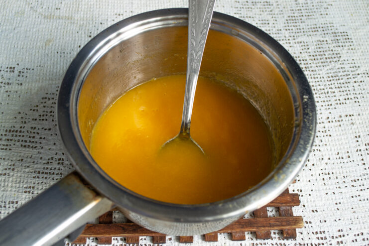 Heating the fruit puree Heating the smooth apricot puree in a saucepan over the stove.