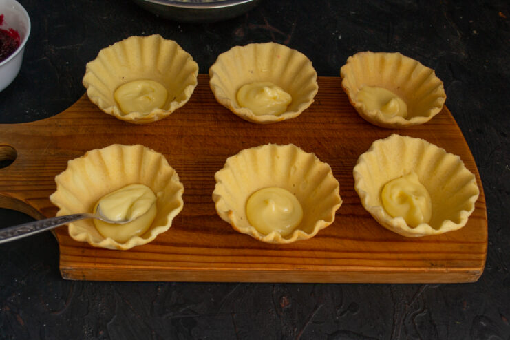 Adding the First Filling Layer Filling shortbread tartlets with buttercream using a teaspoon