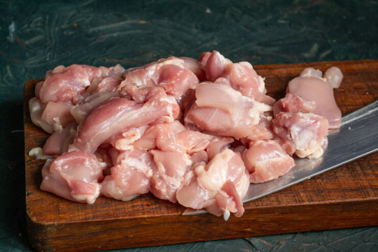 Prepping The Chicken Cubed raw, boneless, skinless chicken thighs on a cutting board