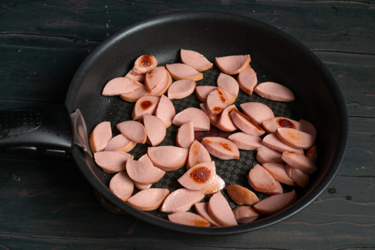 Sautéing The Sausages Thick sausage slices frying in a skillet