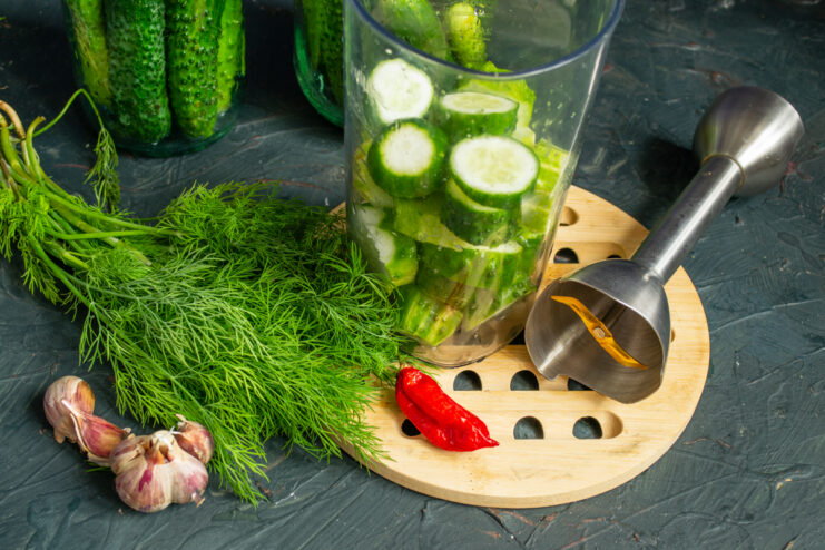 Preparing ingredients for spicy brine Chopped cucumbers, fresh dill, garlic cloves, and habanero pepper inside a blender