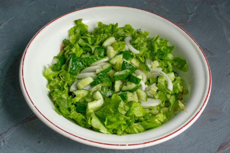 Adding Fresh Cucumbers Chopped cucumbers added to the bowl of greens