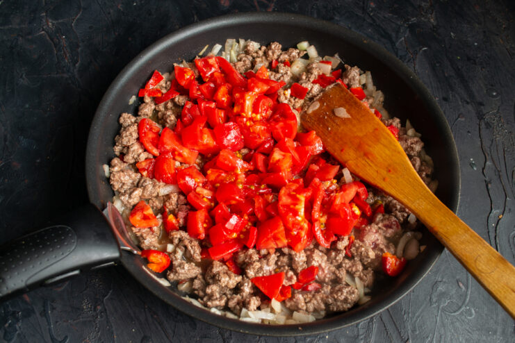 Adding diced tomatoes Freshly diced tomatoes stirred into the meat and vegetable mixture.
