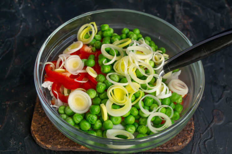 Adding Leek Sliced leek rounds scattered over the fresh salad vegetables