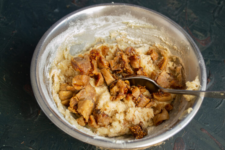Folding figs into the batter Finely chopped dried figs being stirred into the thick muffin batter.
