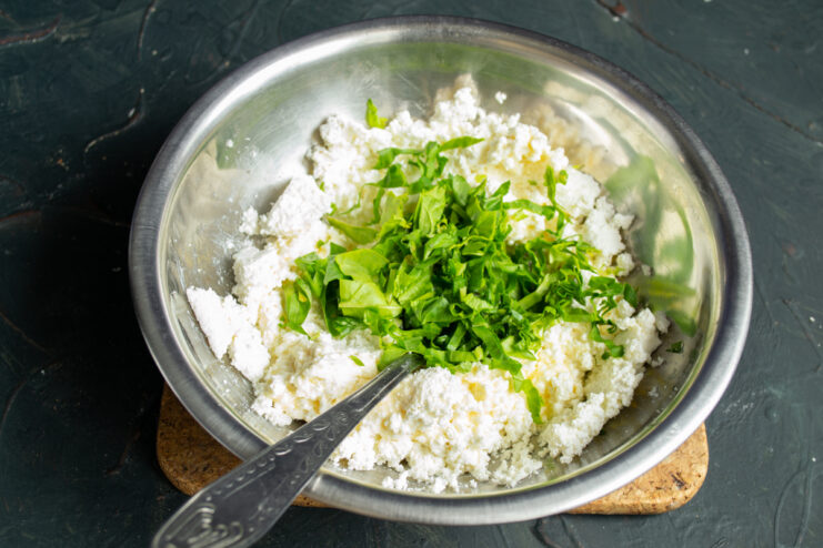 Mixing in fresh spinach for color and vitamins Finely chopped fresh spinach placed in a bowl with the cheese mixture