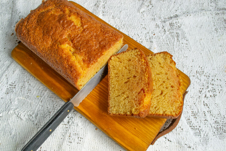 Slicing the Cake Slicing a golden cornmeal loaf cake into portions with a knife.