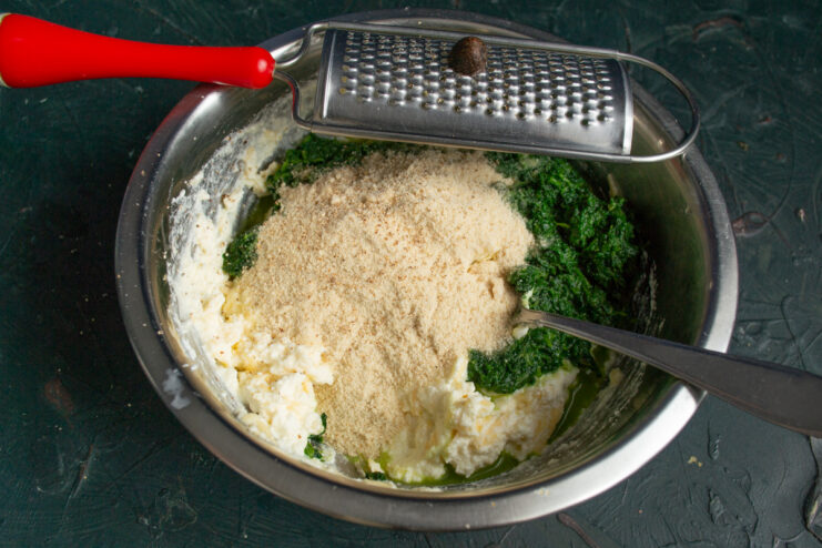 Grating fresh nutmeg Grating fresh whole nutmeg over the spinach mixture