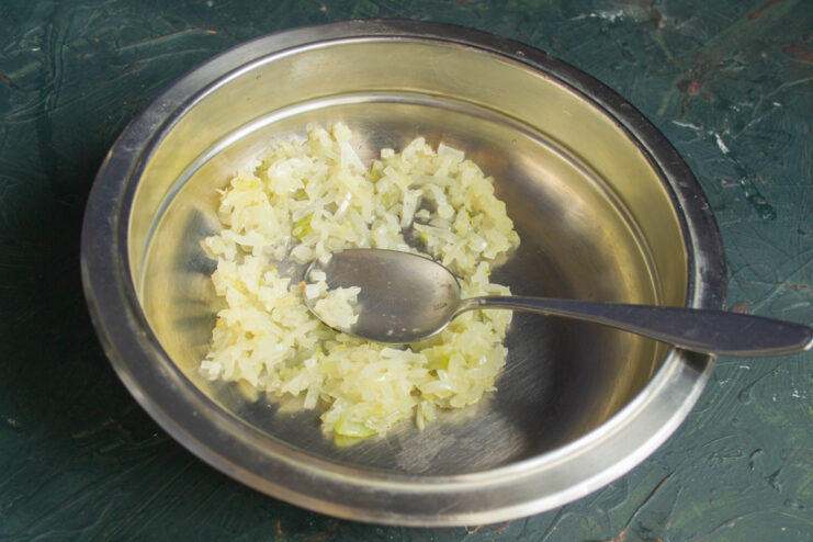 Sauteing the onions Translucent sauteed diced onions in a metal mixing bowl