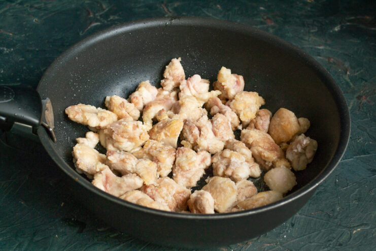 Searing The Meat Browning starch-coated chicken pieces in a hot skillet