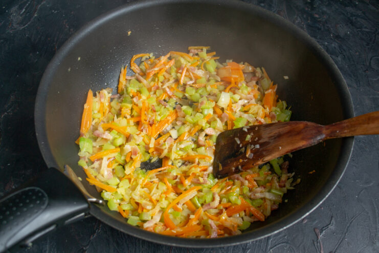 Sautéing vegetables until tender for the soup base Sautéing bacon, carrots, and diced celery in a frying pan