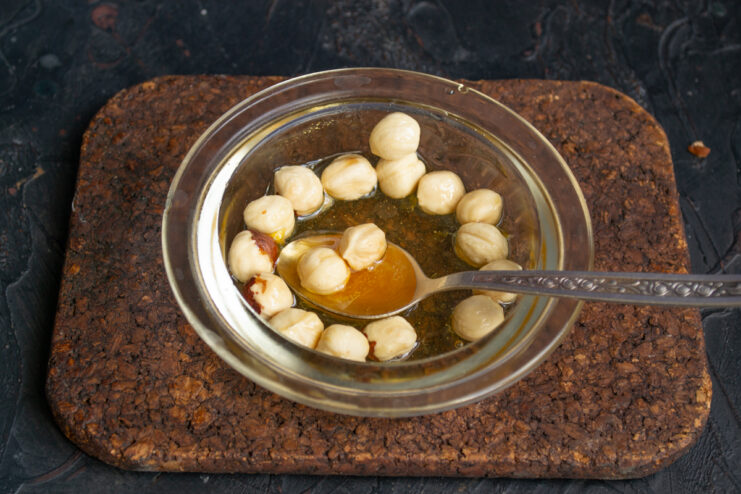 Honey hazelnut filling Peeled hazelnuts mixed with liquid honey in a glass bowl.