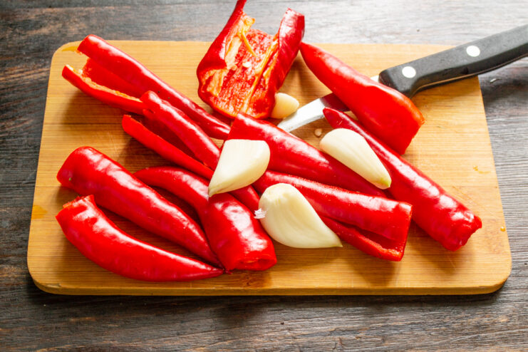 Prepping Garlic And Peppers Peeled garlic cloves and red chili peppers on a board