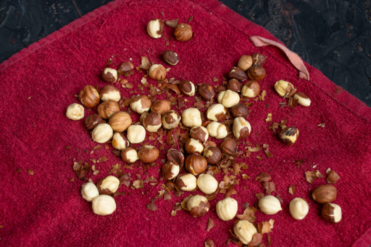 Peeling the nuts Peeled toasted hazelnuts on a red kitchen towel.