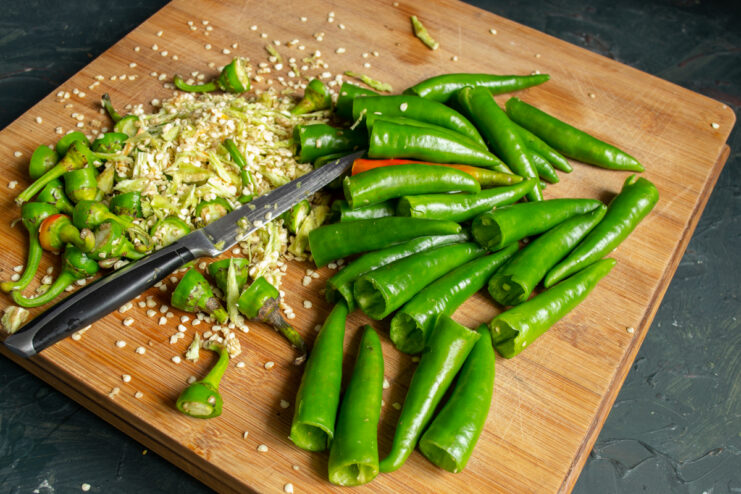 Prepping the chili pods Deseeding fresh green chili peppers on a cutting board
