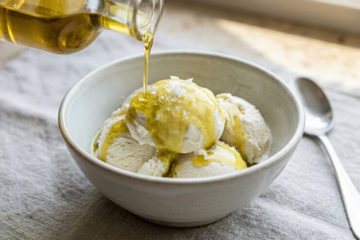 Vanilla Ice Cream Drizzled With Olive Oil Olive oil drizzled over scoops of vanilla ice cream sprinkled with sea salt