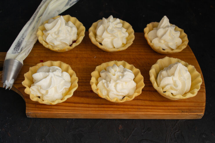 Piping the Whipped Cream Piping whipped cream from a pastry bag onto tartlets