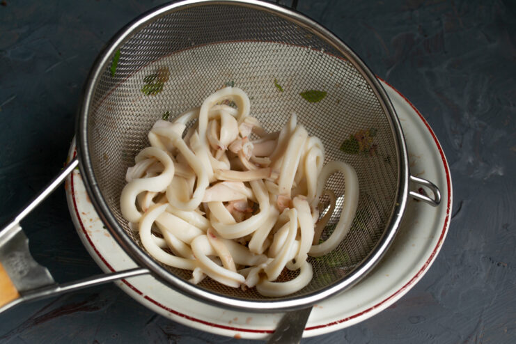 Boiling and Chilling the Squid Boiled squid rings draining in a sieve