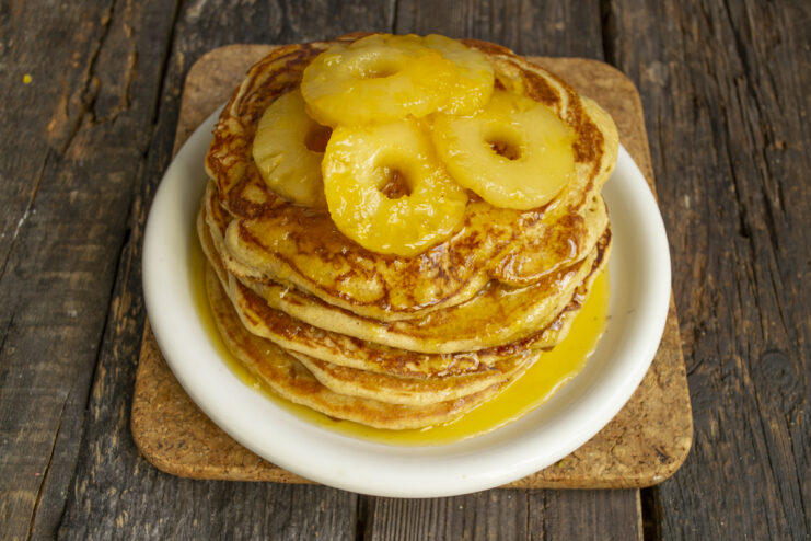 Final Serving Plated pancakes topped with pineapple rings and orange syrup