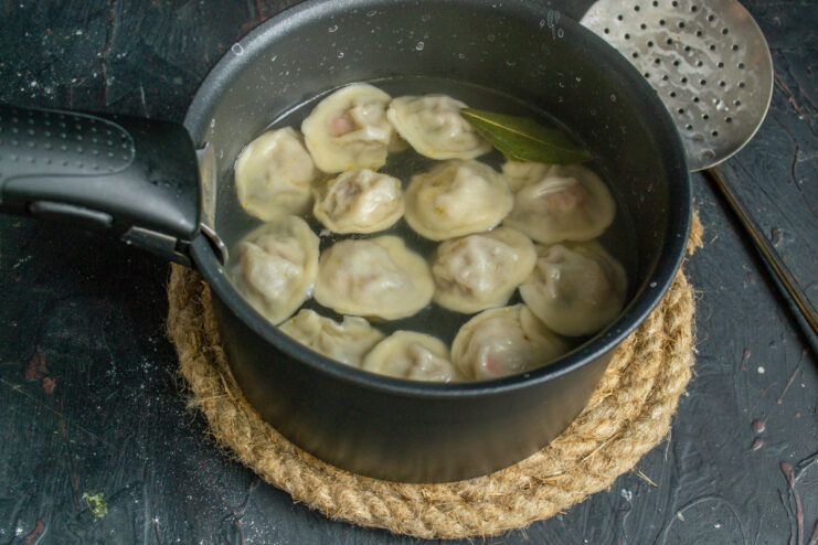 Boiling dumplings in spiced water Dumplings boiling in a pot of water with a bay leaf
