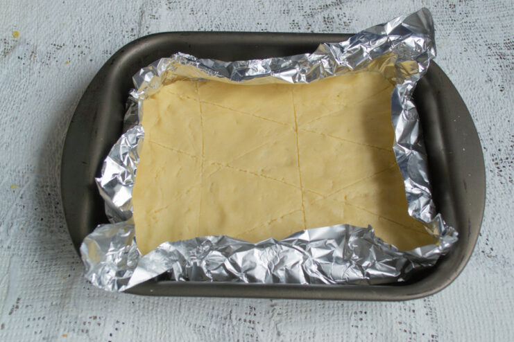 Preparing the Pie Base Bottom layer of dough placed in a foil-lined pan and pricked with a fork.