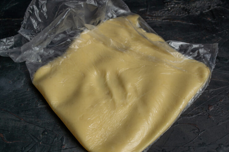 Shortbread dough flattened into a disk and wrapped in clear plastic cling film.