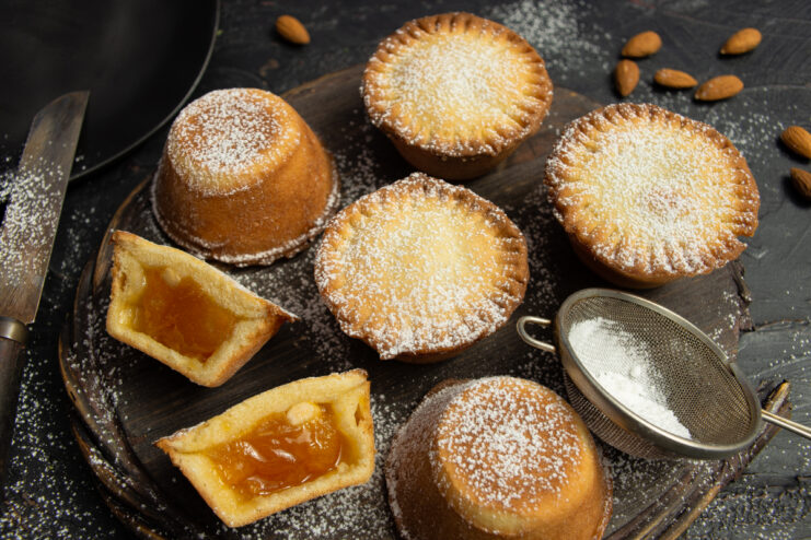 Baked shortbread tartlets filled with jam and almonds dusted with powdered sugar.