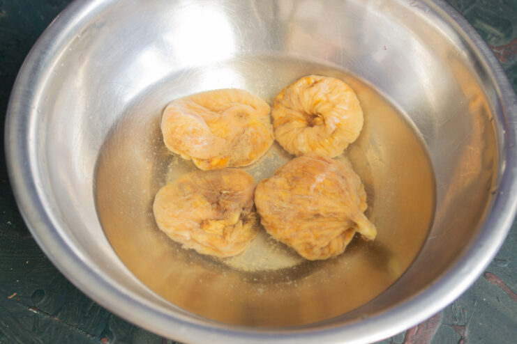 Soaking the figs Dried figs soaking in a bowl of hot water to soften.