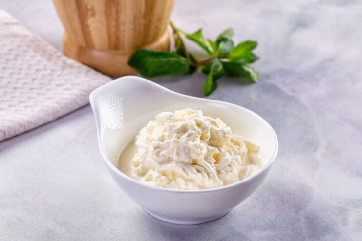 Creamy Italian stracciatella cheese in a bowl. Close-up of fresh Italian stracciatella cheese with shreds of mozzarella soaked in cream.