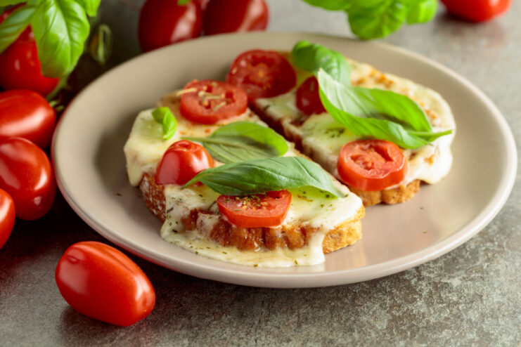 Perfectly melted mozzarella stretching over a warm slice of toasted bread. Melted mozzarella cheese stretching in long, gooey threads from a piece of toasted bread.