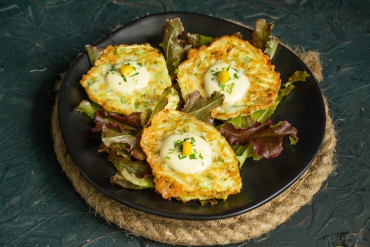 Serving The Dish Plated zucchini fritters served on lettuce leaves with corn kernels