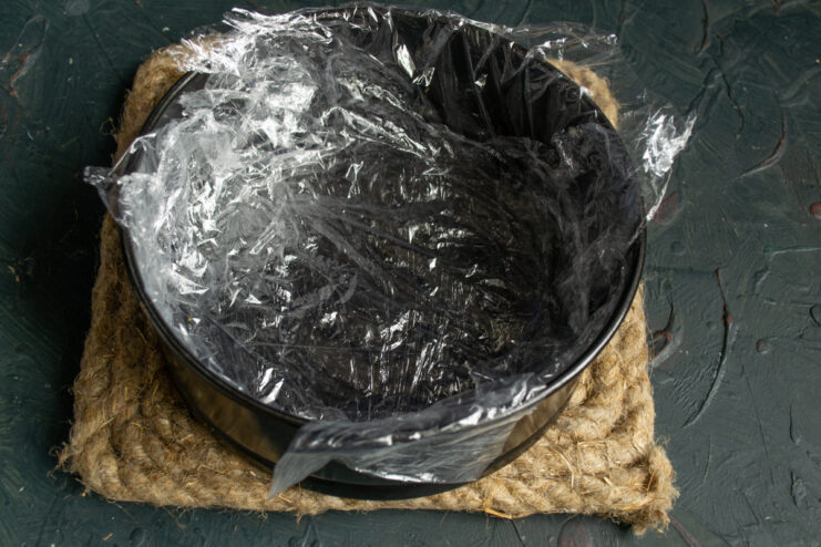 Lining the springform pan Preparing a round springform cake pan by lining it with plastic wrap