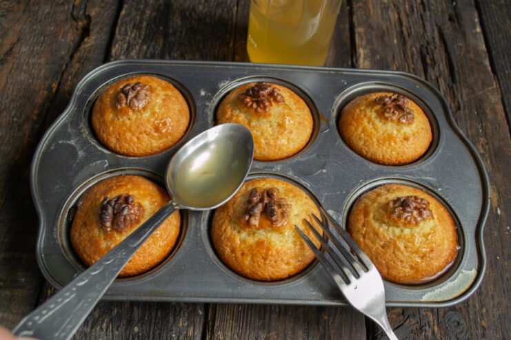 Soaking with lemon syrup Pouring honey-lemon syrup over muffins with a tablespoon