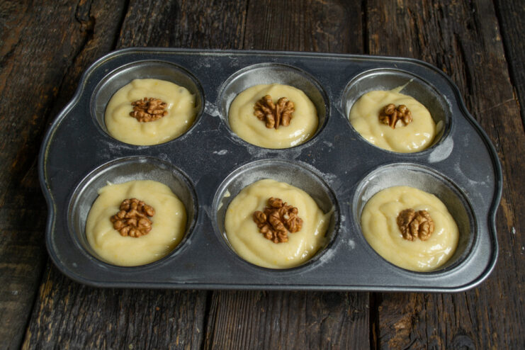 Decorating muffins with walnuts Placing walnut halves on top of the batter in the muffin tin
