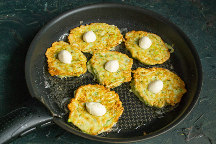 Adding Mozzarella Cheese Placing small mozzarella halves onto the cooking fritters