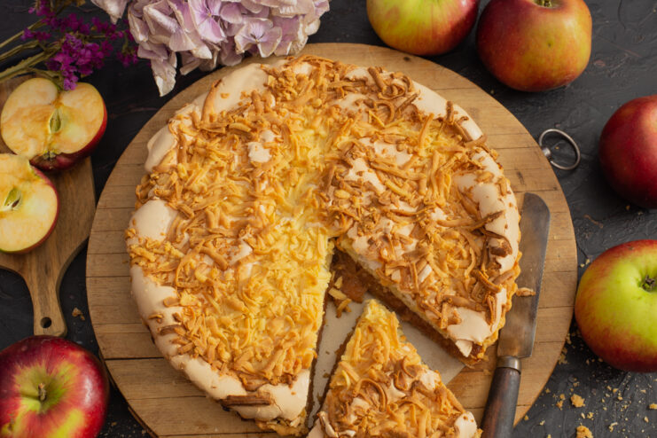 Sliced Polish apple pie with meringue and shortcrust crumb topping on a wooden board