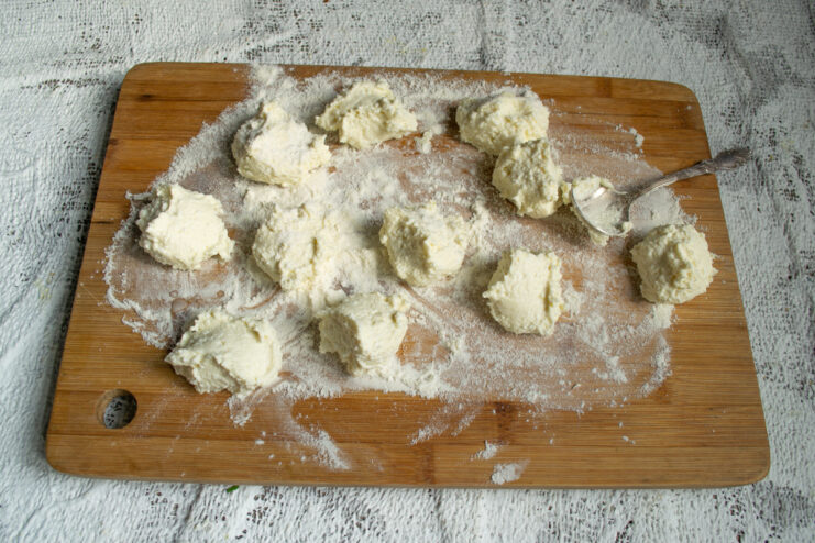 Portioning The Dough Dropping spoonfuls of dough onto a flour-dusted wooden board
