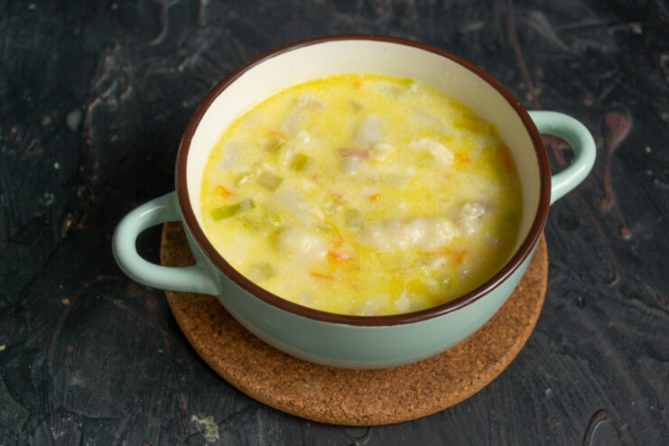 Serving the hot soup with fresh herbs Hot creamy soup with dumplings served in a bowl with fresh garnish