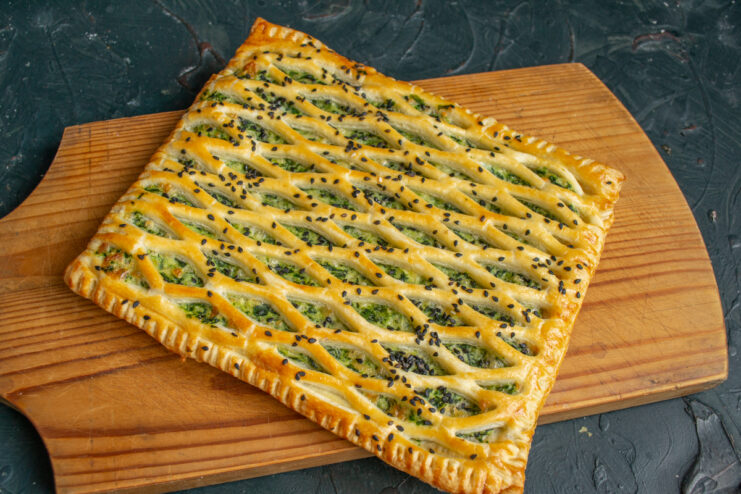 Serving the finished tart A slice of golden spinach and ricotta tart on a wooden board