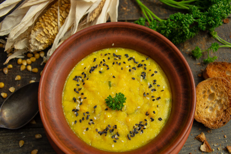 Vegan corn soup in a clay bowl with herbs and sesame seeds