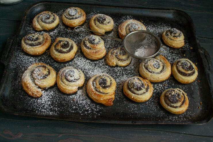Dusting with powdered sugar Dusting hot baked pinwheels with powdered sugar through a fine sieve.
